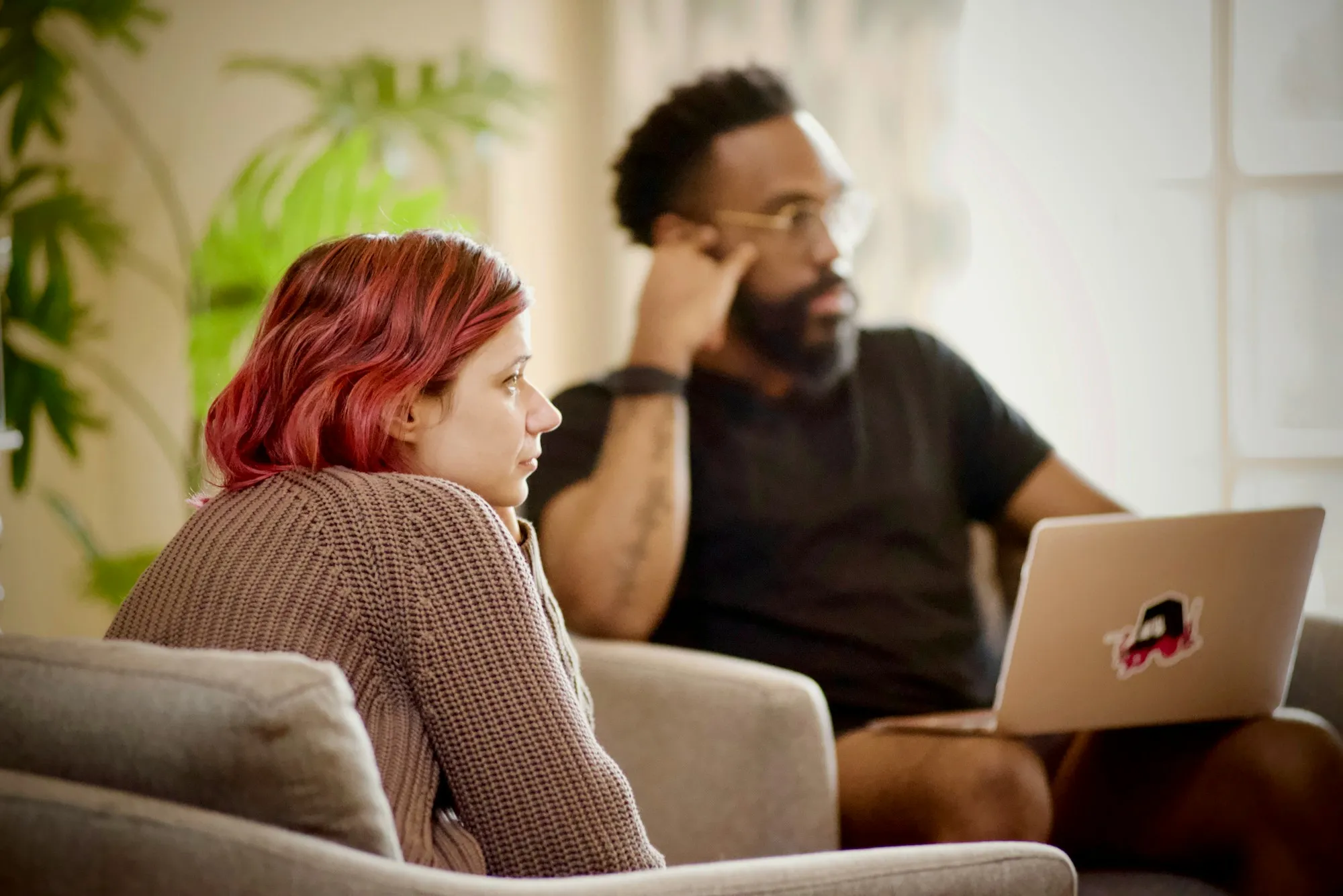 Man looking worried at his laptop while his partner talks through the numbers